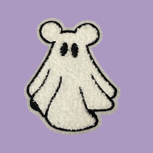May include: White fuzzy ghost with black eyes and a black outline. The ghost has two small ears on top of its head.