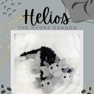 May include: A gray and black plush toy hydra dragon with three heads. The toy is lying on a white fluffy surface. The text "Helios THE HYDRA DRAGON" is above the toy.