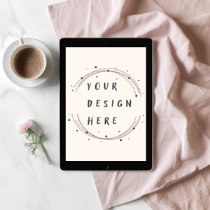 Può includere: Un tablet nero con sfondo bianco e il testo "YOUR DESIGN HERE" in un cerchio con linee marroni e punti neri.