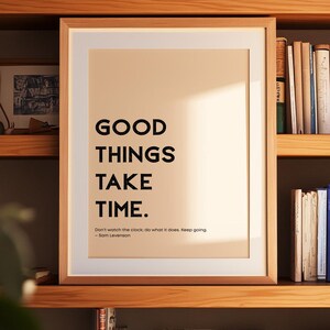 Puede incluir: Un cartel enmarcado con el texto "GOOD THINGS TAKE TIME" en letras negras en negrita. Debajo, la cita "Don't watch the clock: do what it does. Keep going. - Sam Levenson." El marco es marrón claro y el fondo es beige neutro.