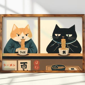 Könnte beinhalten: Eine gerahmte Illustration von zwei Katzen, die Ramen essen. Die Katze links ist orange und trägt eine blaue Robe. Die Katze rechts ist schwarz und trägt eine schwarze Robe. Beide Katzen halten Essstäbchen und essen Ramen aus Schüsseln. Der Text auf den Schüsseln lautet "Ramen" und "Soba". Der Text auf dem Schild unter den Katzen lautet "Ramen", "Soba" und "Hatto".