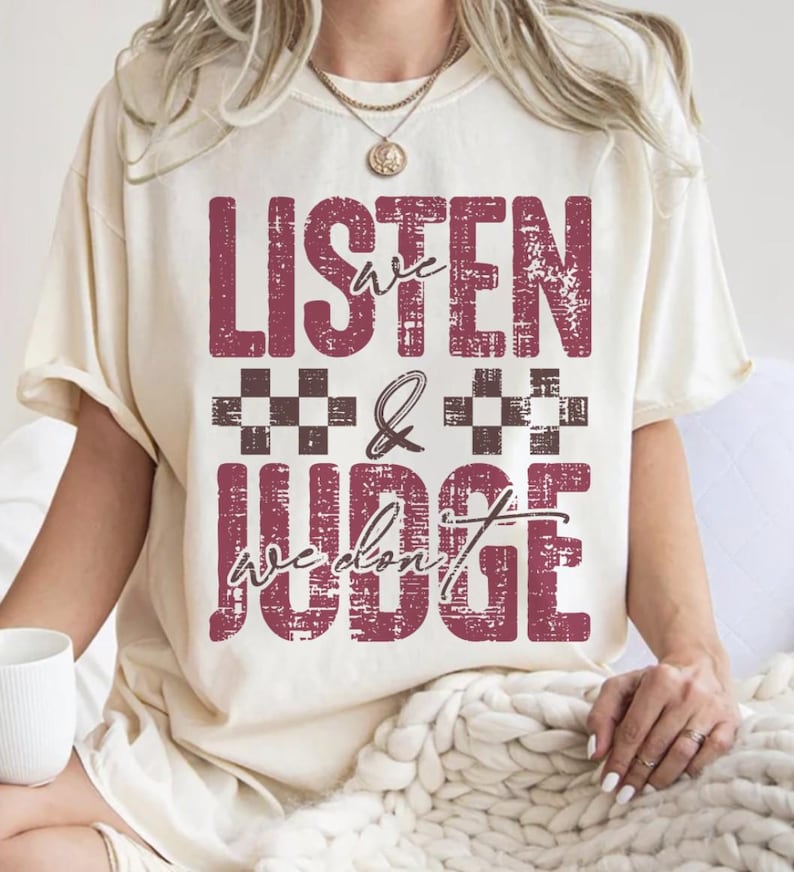 May include: A white t-shirt with a distressed red graphic that says "We Listen & We Don't Judge".