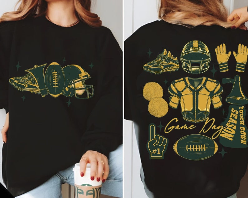 May include: Black sweatshirt with a green and gold football theme design. The design includes a football, helmet, shoe, and other football-related imagery. The text "Game Day" is included in the design.