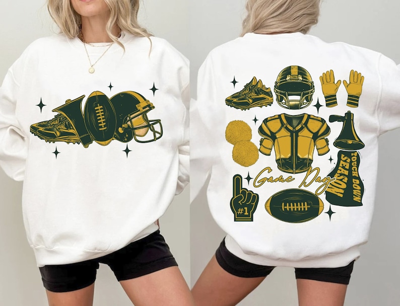 May include: White sweatshirt with a green and gold football theme. The front of the sweatshirt has a football, helmet, and shoe. The back of the sweatshirt has a football helmet, football, megaphone, pom poms, and the text "Game Day Touch Down Season".