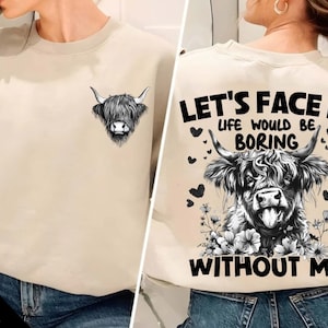 May include: A beige sweatshirt with a black and white illustration of a Highland cow's head on the front and a black and white illustration of a Highland cow with the text "Let's Face It Life Would Be Boring Without Me" on the back.