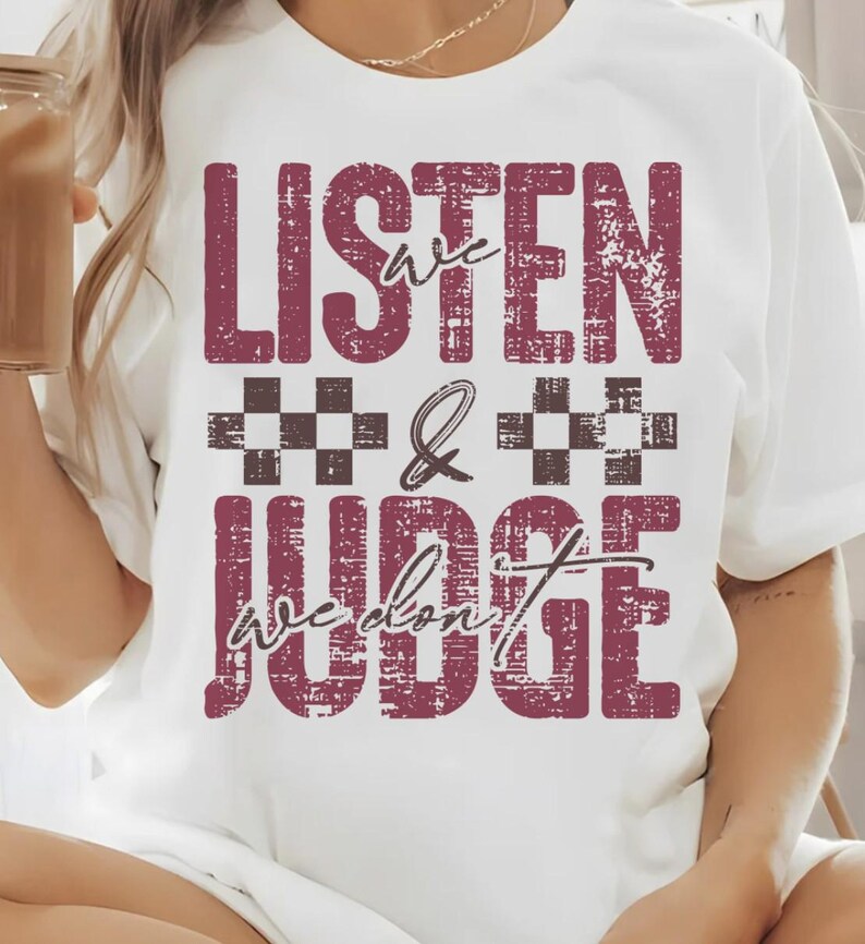 May include: White t-shirt with a maroon distressed graphic that says "Listen we don't judge" with a checkered pattern between the words.