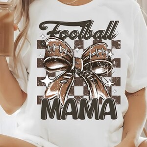 May include: White t-shirt with a brown football-shaped bow and the text "Football Mama" on a checkered background.