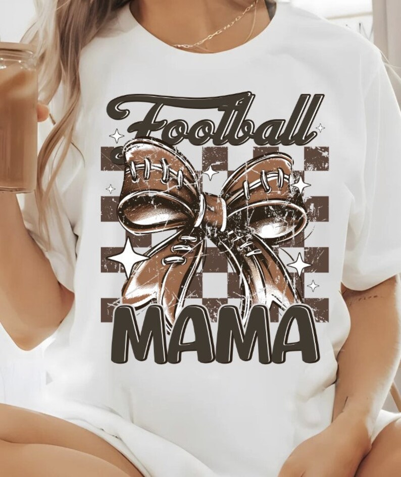 May include: White t-shirt with a brown football-shaped bow and the text "Football Mama" on a checkered background.