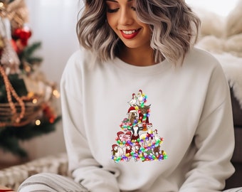 Peut inclure: Un sweat-shirt blanc avec un motif d'arbre de Noël représentant divers animaux de ferme, dont des poulets, des cochons, des vaches et un chapeau de Père Noël. L'arbre est décoré de lumières colorées.