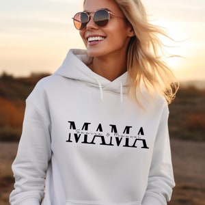 Könnte beinhalten: Weißer Hoodie mit schwarzem Text, der "MAMA" lautet, mit den Namen "Samira & Manuel" darunter.