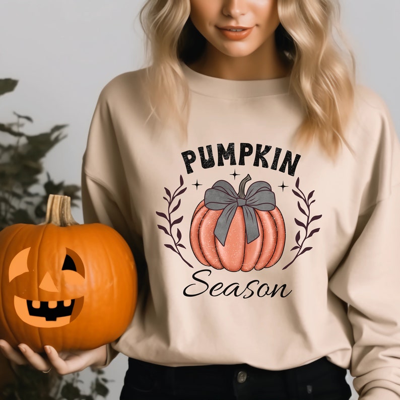 May include: A beige sweatshirt with a graphic of a pumpkin with a bow and the text "Pumpkin Season".