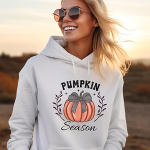 May include: White hoodie with a graphic of a pumpkin with a gray bow and the text "Pumpkin Season" in black.