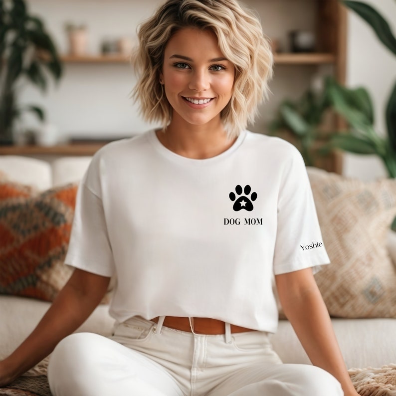 May include: White t-shirt with a black paw print and the text "DOG MOM" on the front. The text "Yoshie" is on the sleeve.