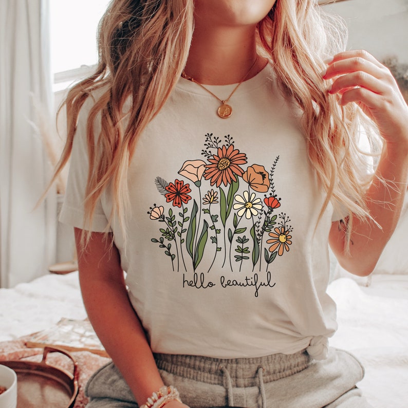 May include: White t-shirt with a floral design and the text "hello beautiful".