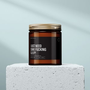 May include: A brown glass candle jar with a gold lid. The label reads "I just need some fucking sleep!" Hand poured in small batches. 9 oz / 252 g.