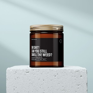 May include: A brown glass candle jar with a gold lid. The label reads "OH SHIT! CAN YOU STILL SMELL THE WEED?"  Hand poured in small batches. 9 oz / 252 g.