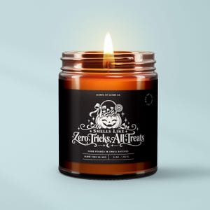 May include: A lit candle in an amber glass jar with a black label. The label features a white graphic of a jack-o'-lantern filled with candy and the text: Scents of Satire Co. Smells Like Zero Tricks, All Treats. Hand poured, 50 hrs, 9 oz / 252 g.