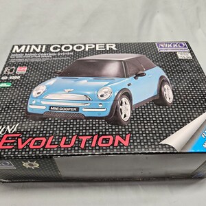 May include: A blue Mini Cooper toy car in a box with the text "MINI COOPER EVOLUTION" and "NIKKO" on it. The box has a blue flap that says "FLIP FOR MORE DETAILS!"