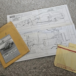 May include: A collection of Mechanix Illustrated Urba Centurion car building plans including a large white technical blueprint, a grey instructional booklet with a car illustration, a tan envelope, and a yellow perforated paper form with red lines.