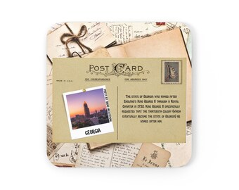 Könnte beinhalten: Eine Vintage-Postkarte mit einem Foto der Skyline von Atlanta bei Sonnenuntergang. Die Rückseite der Postkarte enthält Text über die Geschichte Georgiens und wie es nach König Georg II. benannt wurde. Die Postkarte wurde in den USA hergestellt.