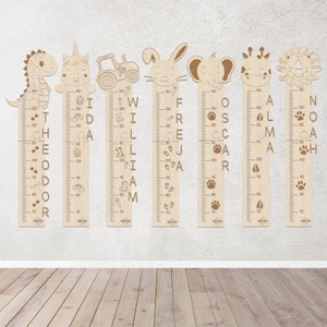 May include: Wooden growth charts with animal toppers, including a dinosaur, unicorn, tractor, rabbit, elephant, giraffe, and lion. Each chart features a name and height markings up to 130 cm, with decorative elements like paw prints and carrots.