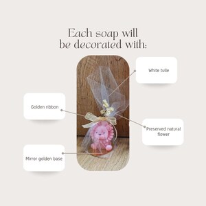 May include: A pink lion-shaped soap is wrapped in white tulle and tied with a golden ribbon. The soap sits on a mirror golden base and is decorated with a preserved natural flower. Text reads: Each soap will be decorated with: