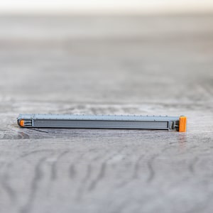 May include: A grey and orange plastic drawer slide. The slide is designed to be used in a drawer to help it open and close smoothly.