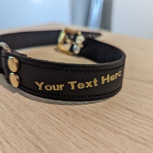 Puede incluir: Collar de perro de cuero negro con detalles en metal dorado y el texto "Your Text Here" bordado en oro.