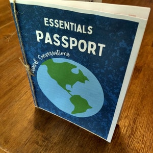 Op de afbeelding: Een blauwe paspoorthoes met de tekst "Essentials Passport" en "Casual Conversations". De hoes heeft een wereldbol met een groene landmassa en een blauwe oceaan.