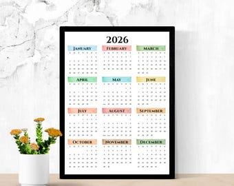 Könnte beinhalten: Ein Wandkalender für 2026 in einem schwarzen Rahmen mit zwölf Monaten in einem Raster. Jeder Monatskopf ist in einem einzigartigen, pastellfarbenen Aquarell-Block dargestellt, mit schwarzem Text für die Wochentage und die Daten.