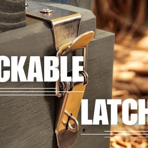 K&ouml;nnte beinhalten: Ein silberfarbener Metall-Schnappverschluss an der Kante einer dunkelgrauen Holzkiste. Der Beschlag verf&uuml;gt &uuml;ber einen klappbaren Hebelmechanismus mit einer kleinen &Ouml;se f&uuml;r ein Vorh&auml;ngeschloss. Der Text LOCKABLE LATCHES ist in wei&szlig;en Gro&szlig;buchstaben eingeblendet.