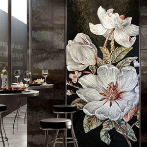 May include: A mosaic tile artwork depicting large white magnolia flowers with brown centres and green leaves against a black background. The mosaic is detailed and realistic, with a variety of tile sizes. The artwork is displayed in a modern setting.