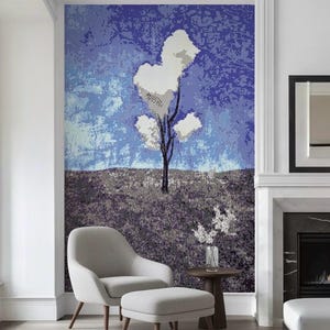 May include: A large mosaic wall art piece depicting a stylized tree with white, heart-shaped leaves against a blue sky. The artwork is installed above a gray armchair and ottoman, with a small table and vase of flowers.