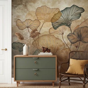 Könnte beinhalten: Ein Raum mit einem botanischen Wandbild in Braun-, Beige- und Grüntönen. Unter dem Wandbild befindet sich eine grüne Kommode mit zwei Schubladen und einem Holzrahmen. Eine weiße Vase mit getrockneten Pflanzen und eine Holzskulptur stehen darauf. Rechts steht ein Korbstuhl mit gelbem Kissen.