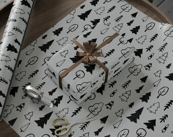May include: A white gift wrap with a black and white pattern of stylized trees. A brown gift box with a gold ribbon is on top of the wrapping paper. A roll of wrapping paper with a similar pattern is in the background.