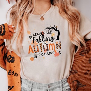 May include: A white t-shirt with a graphic design that says "Leaves are falling & Autumn is calling" with a cute illustration of a tree, leaves, and a cup of coffee.