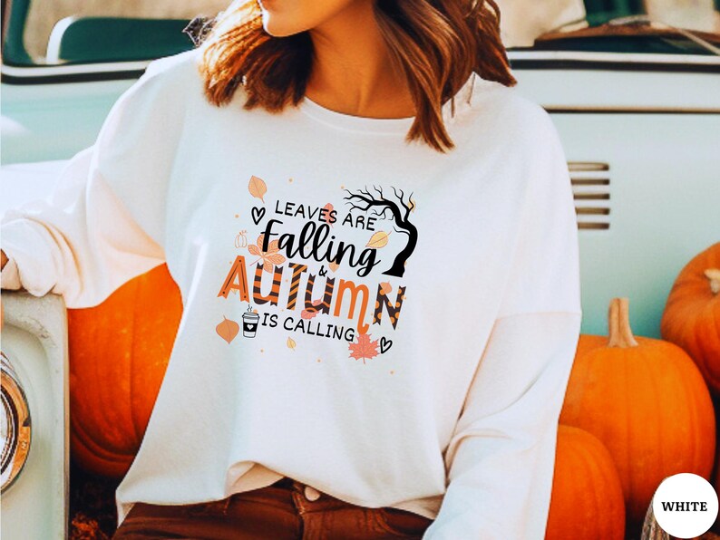 May include: White long-sleeve sweatshirt with a graphic print of leaves falling and the text "Leaves are falling & autumn is calling".