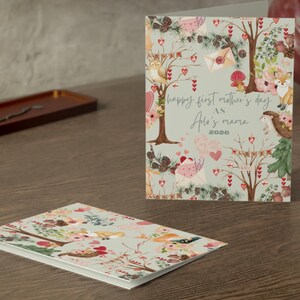 May include: A greeting card with a floral and woodland design, featuring a fox, birds, and hearts. The card reads "Happy First Mother's Day" and "Aria's Mama 2026". A second card with a similar design is visible.