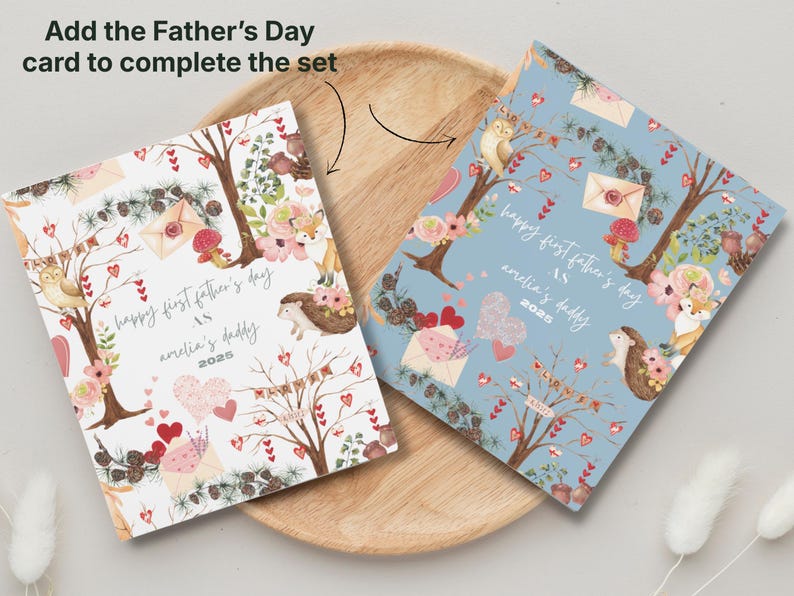 May include: Two Father's Day cards with floral and woodland illustrations. One card is white, the other is light blue. Both cards have the text "happy first father's day as amelia's daddy 2025".