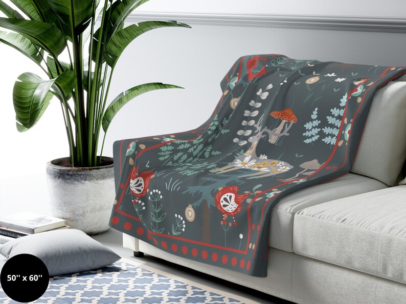 May include: A soft, dark blue throw blanket with a whimsical forest scene featuring a deer, mushrooms, and floral patterns. The blanket has a red and white border with a repeating pattern of dots. The blanket measures 50 inches by 60 inches.