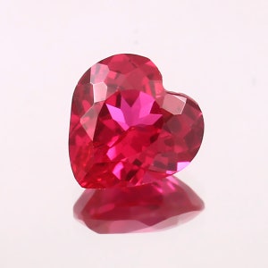 May include: A heart-shaped ruby gemstone with a deep red color and a faceted cut.