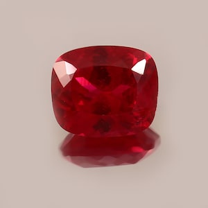 Può includere: Una pietra preziosa di colore rosso intenso con taglio a cuscino. La pietra preziosa è sfaccettata e ha un'alta lucidatura.