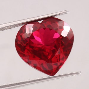 Puede incluir: Una piedra preciosa roja oscura en forma de corazón con un corte facetado.