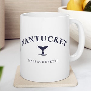 May include: White ceramic coffee mug with a blue whale tail logo and the text "NANTUCKET MASSACHUSETTS".