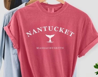 May include: A red t-shirt with a white graphic of a whale tail and the text "NANTUCKET MASSACHUSETTS".