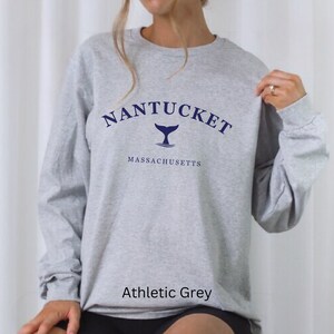 Könnte beinhalten: Ein graues Sweatshirt mit dem Text "NANTUCKET" in einem marineblauen Bogen über einer marineblauen Walflosse. Der Text "MASSACHUSETTS" erscheint in marineblau unter der Grafik. Das Sweatshirt ist mit "Athletic Grey" gekennzeichnet.