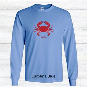 A Carolina Blue unisex long sleeve t-shirt with a graphic of a red crab, above the word crab in lower case font, followed by a period.