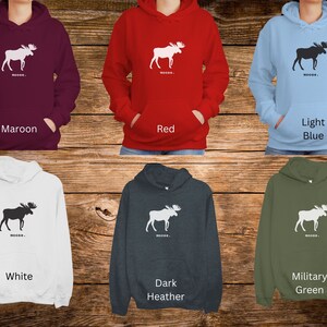 May include: Six different color hoodies with a white moose silhouette and the word "MOOSE..." printed on the front. The colors are maroon, red, light blue, white, dark heather, and military green.