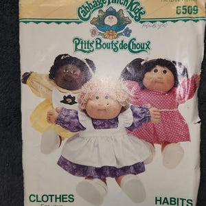 May include: A vintage Cabbage Patch Kids sewing pattern with a white background and green border. The pattern features three Cabbage Patch Kids dolls wearing different outfits. The pattern number is 6509 and the title is "Cabbage Patch Kids P'tits Bouts de Choux".
