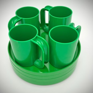 May include: Four bright green plastic mugs with curved handles sit on a matching green tray. The mugs are evenly spaced and appear to be made of a durable plastic material. The tray has a slightly raised edge.